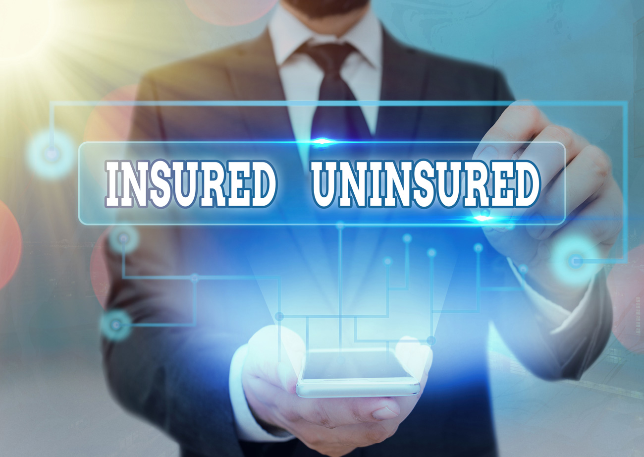 Man pointing at phone with text sign showing “insured” and “uninsured.”