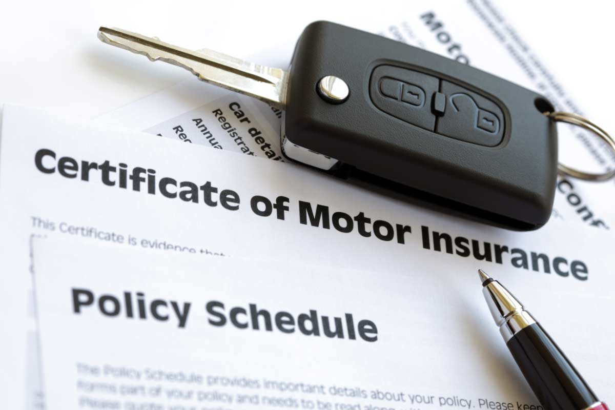 Car key laying on top of certificate of motor insurance and insurance policy schedule